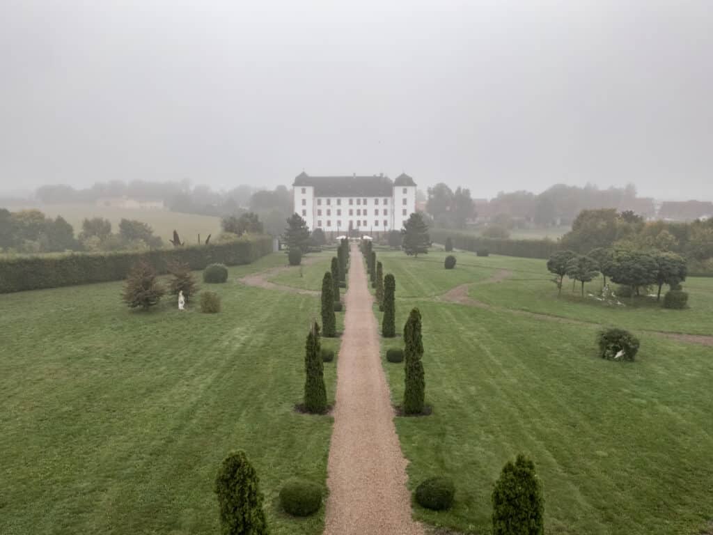 Nebliger Schlosshof mit symmetrischen Gartenwegen