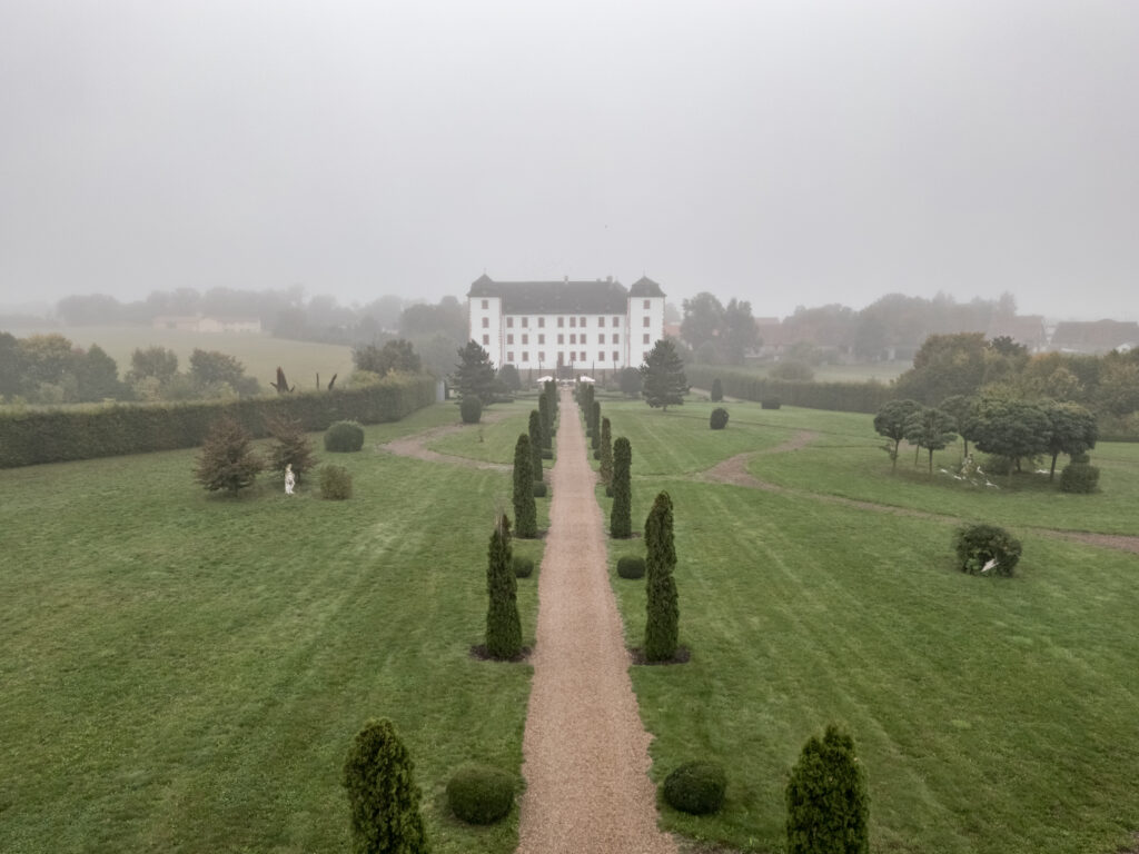 Nebliger Schlosshof mit symmetrischen Gartenwegen