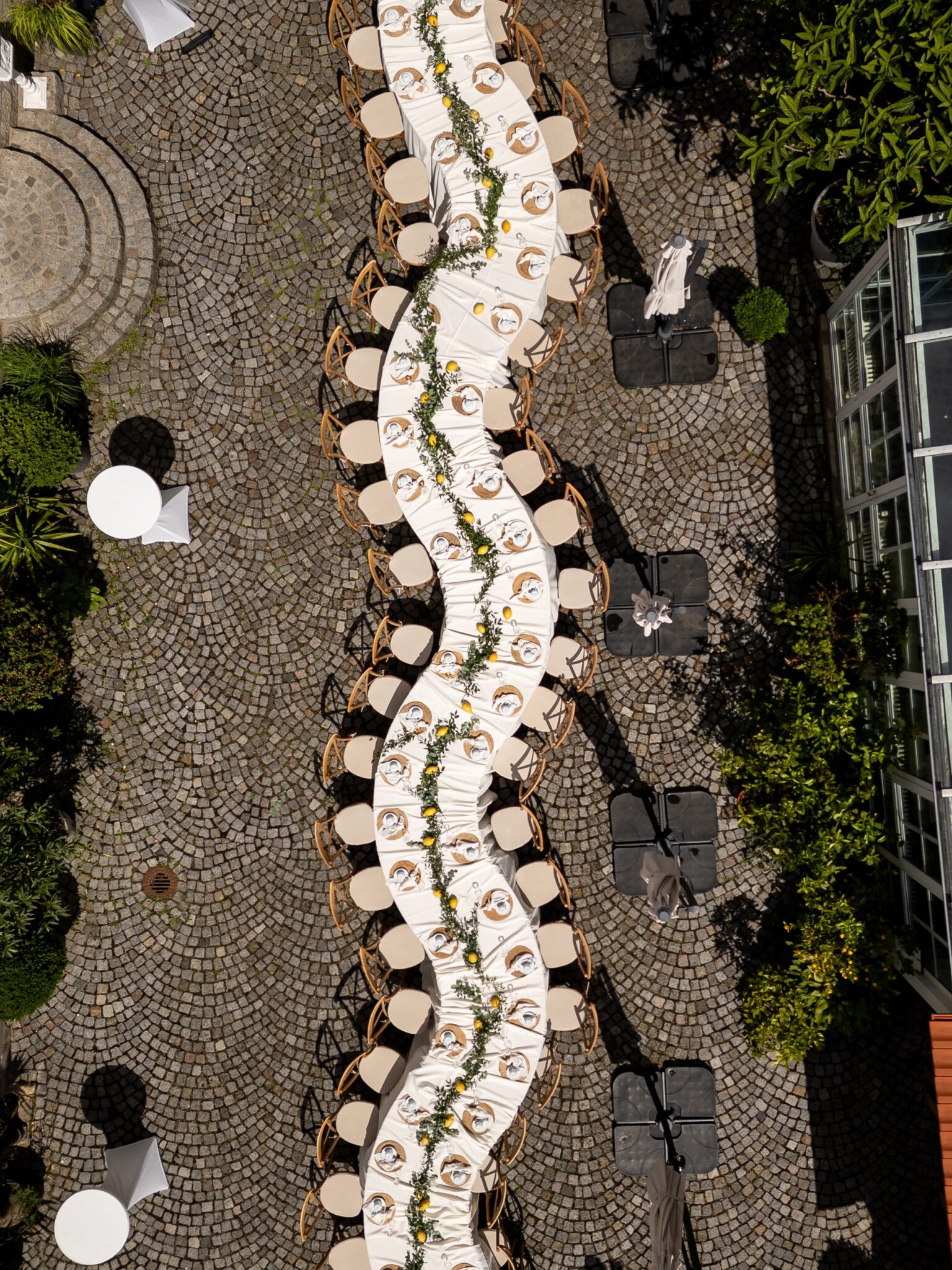 Geschwungene, gedeckte Tafel im Kopfsteinpflasterhof