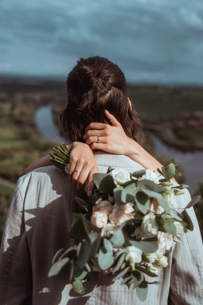 Hochzeitsumarmung mit Blumenstrauß im Freien