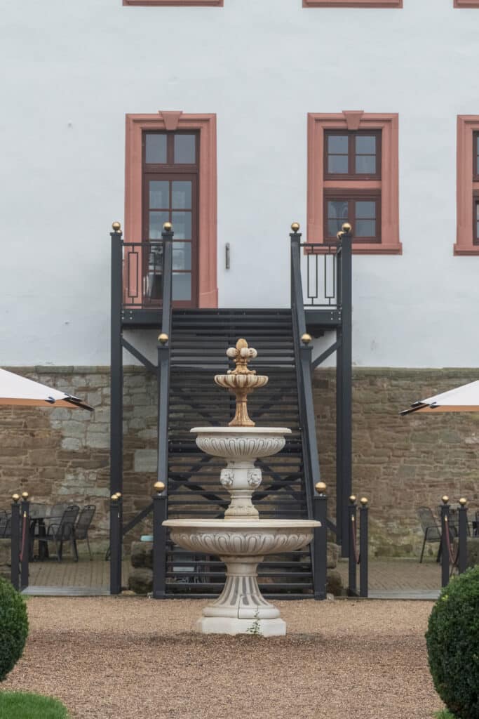 Brunnen vor historischer Gebäudefassade im Garten