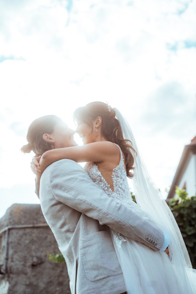 Brautpaar umarmt sich vor hellem Himmel