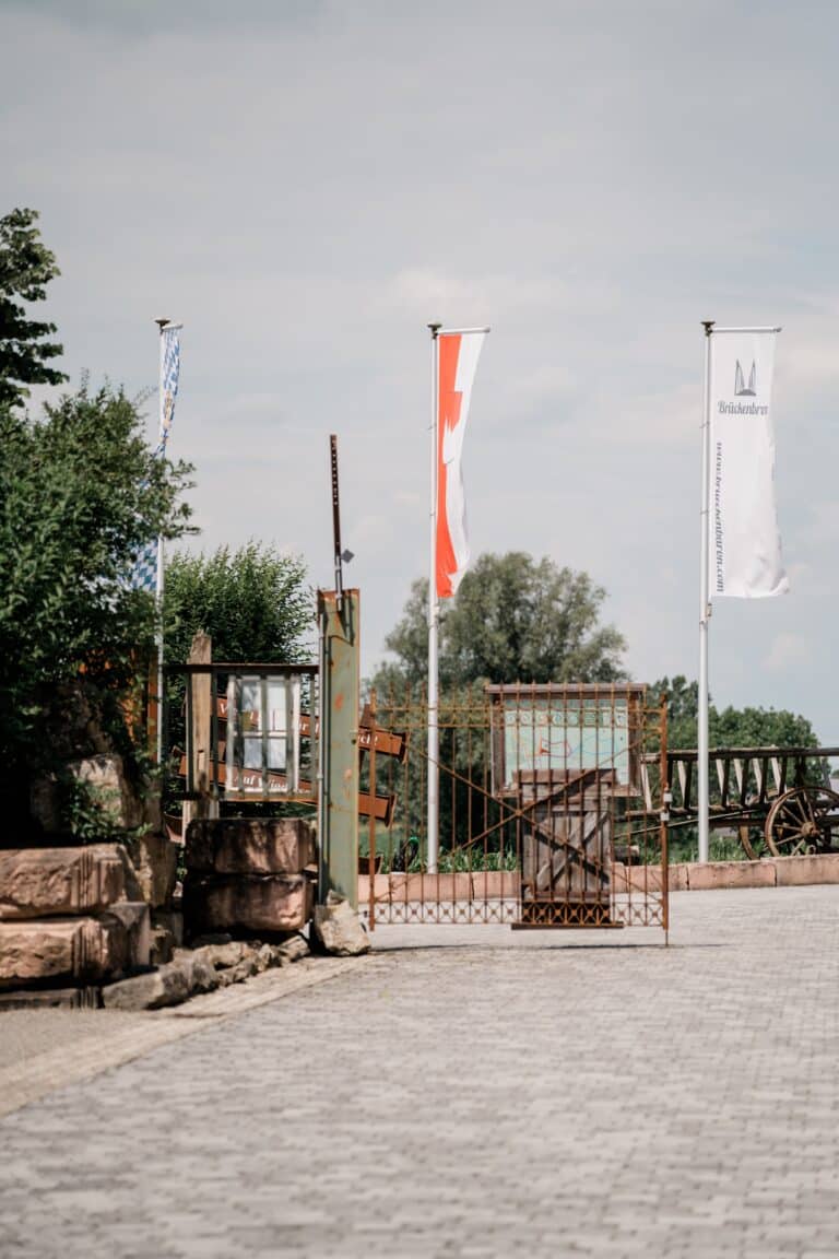 00041-florian-knusper-hochzeitsfotograf-wuerzburg-eingangstor-mit-fahnen-Brückenbaron