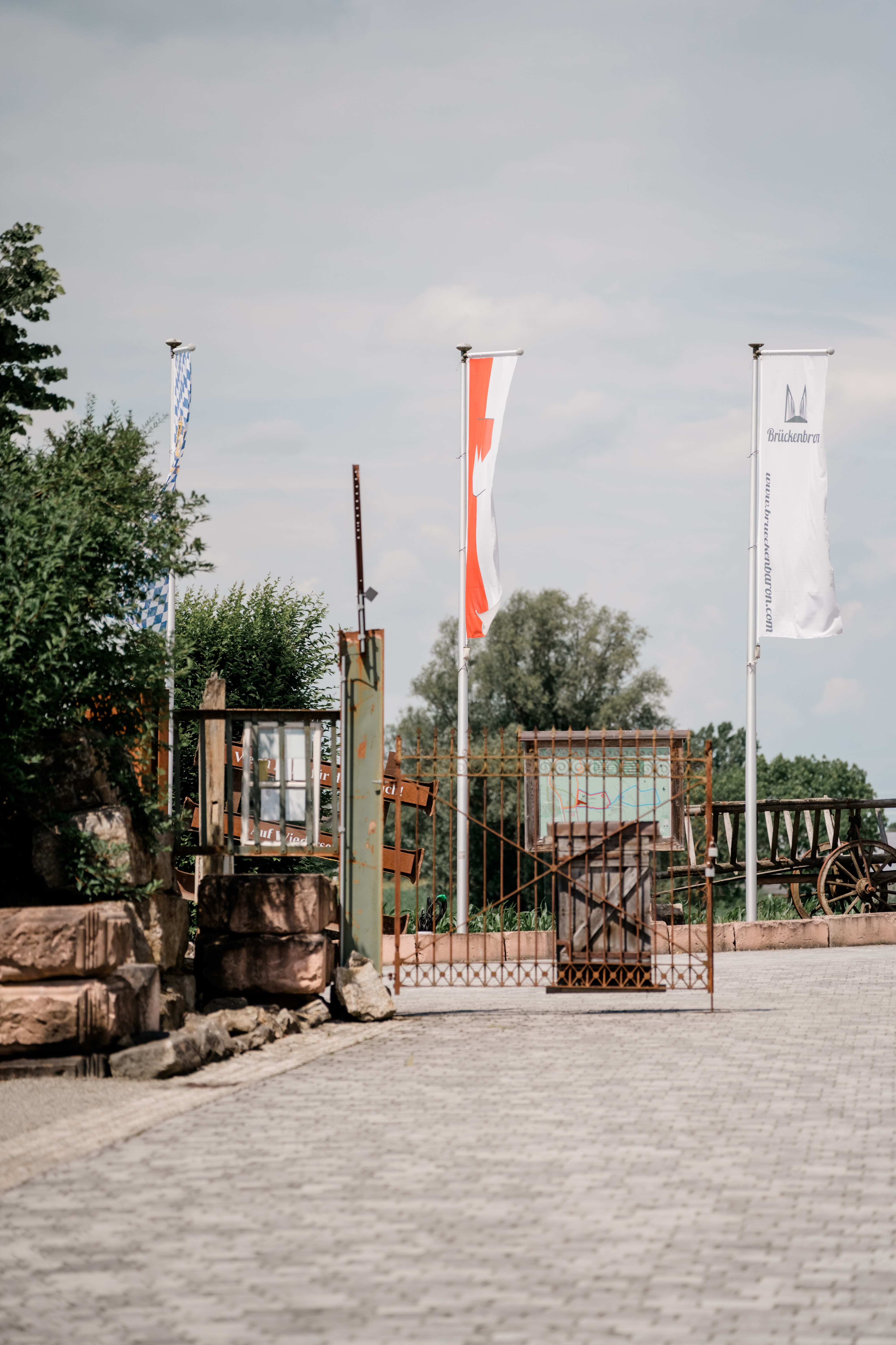 Eingangstor mit Fahnen und Pflanzen im Freien.