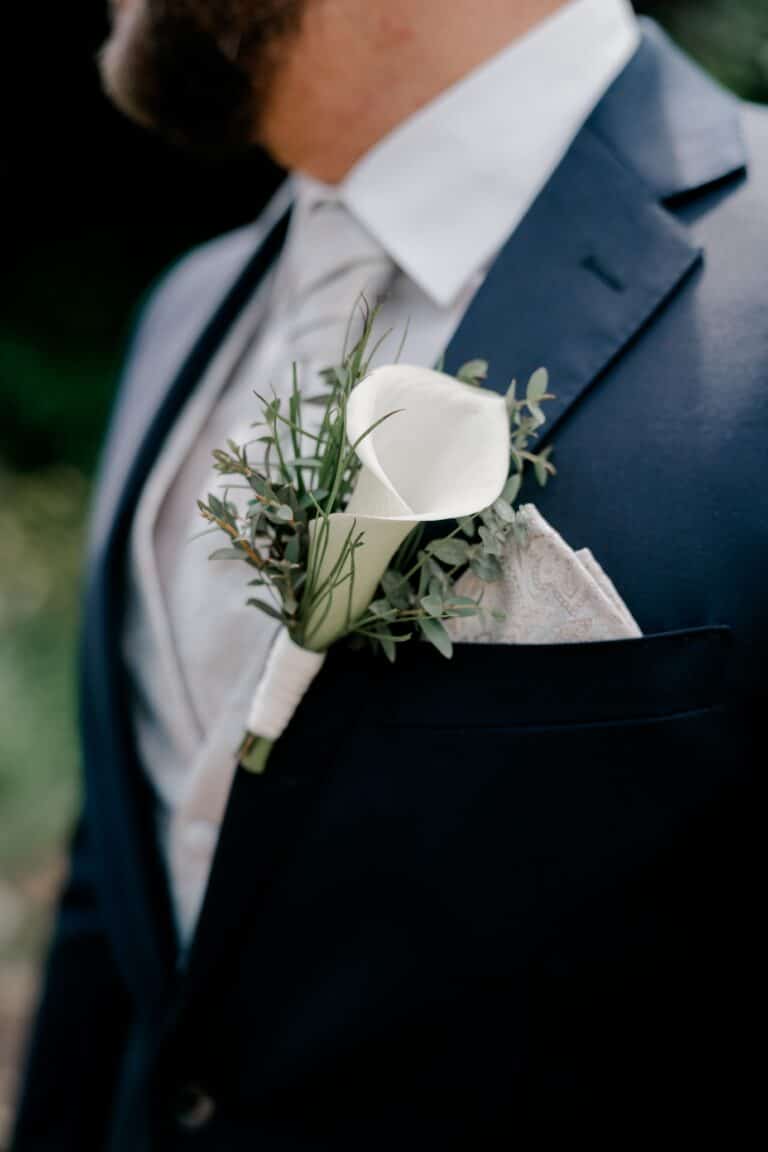 00046-florian-knusper-hochzeitsfotograf-wuerzburg-ansteckblume-am-anzug-Brückenbaron