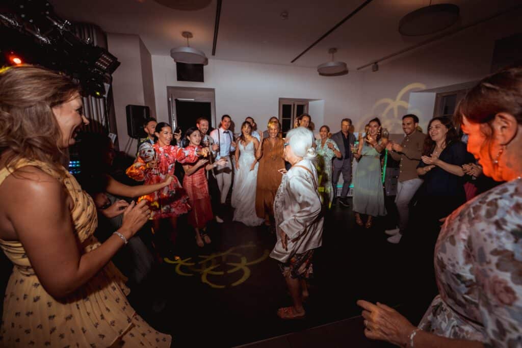 Hochzeitstanz mit fröhlichen Gästen im Festsaal.