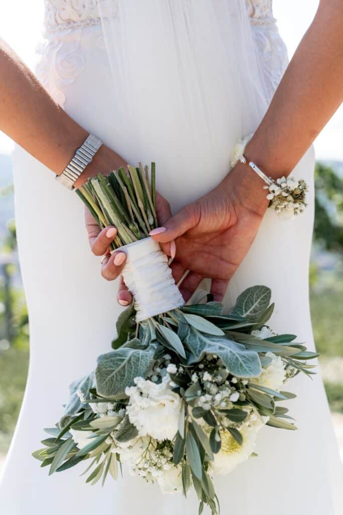 Braut hält Blumenstrauß elegant in weißen Kleid