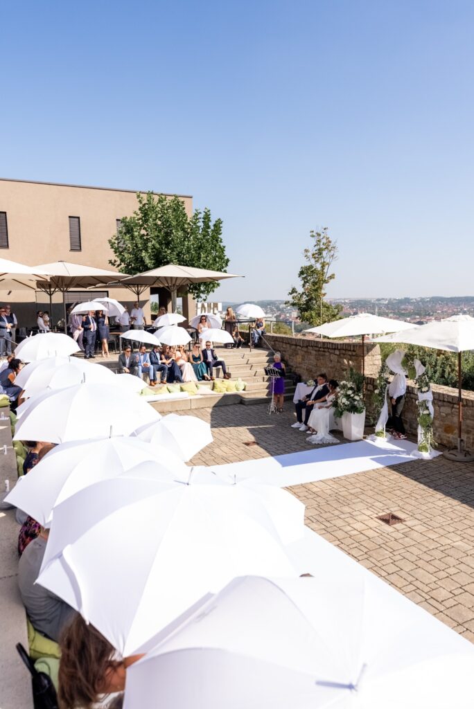 Hochzeitsgäste mit Sonnenschirmen im Freien