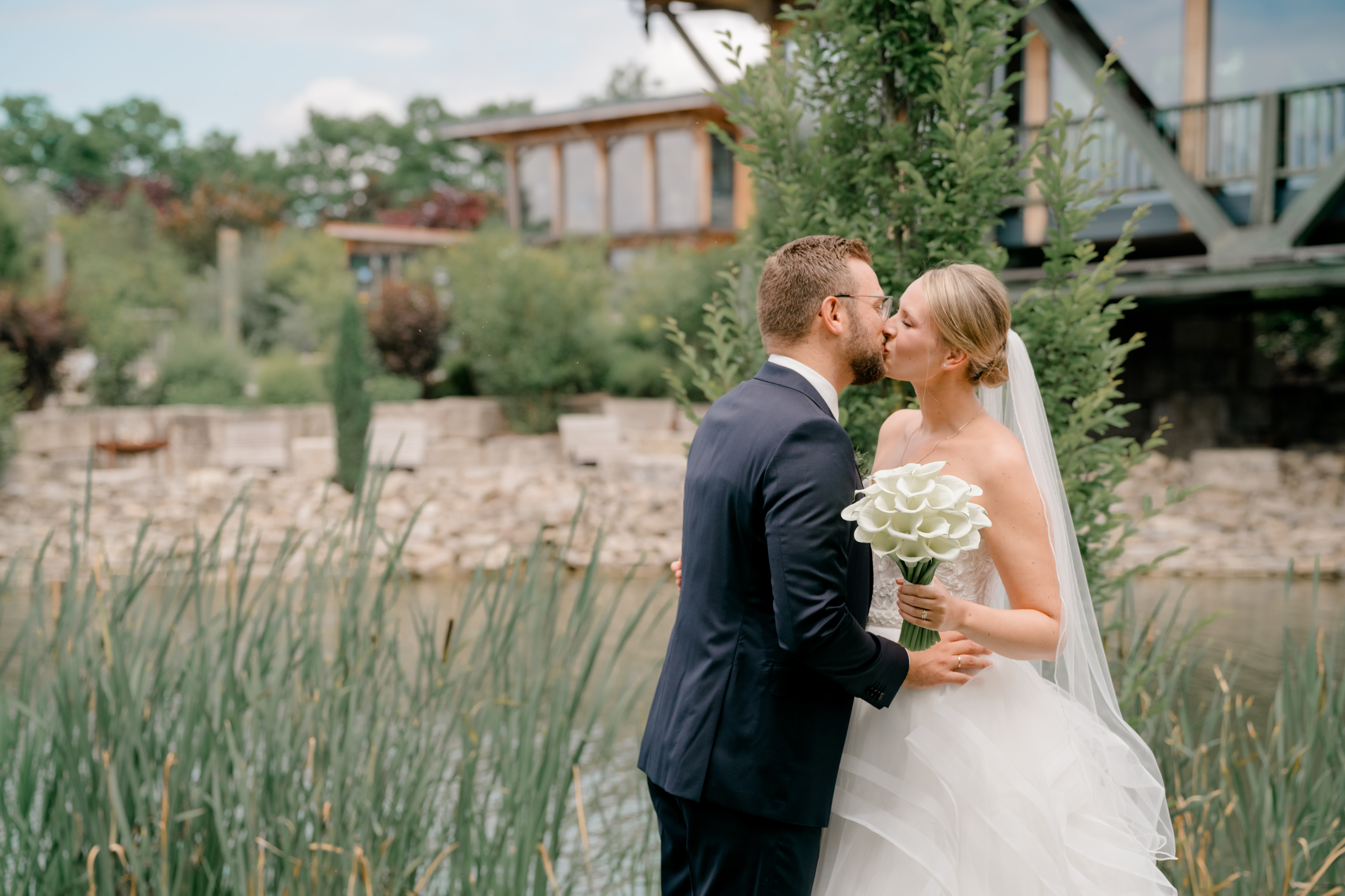 Brautpaar küsst sich vor Landschaftsgarten