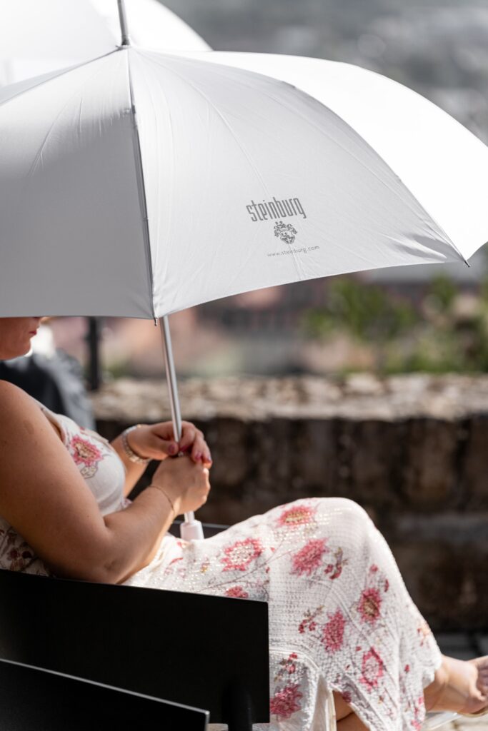 Sitzende Hochzeitsgast mit Sonnenschirm im Garten