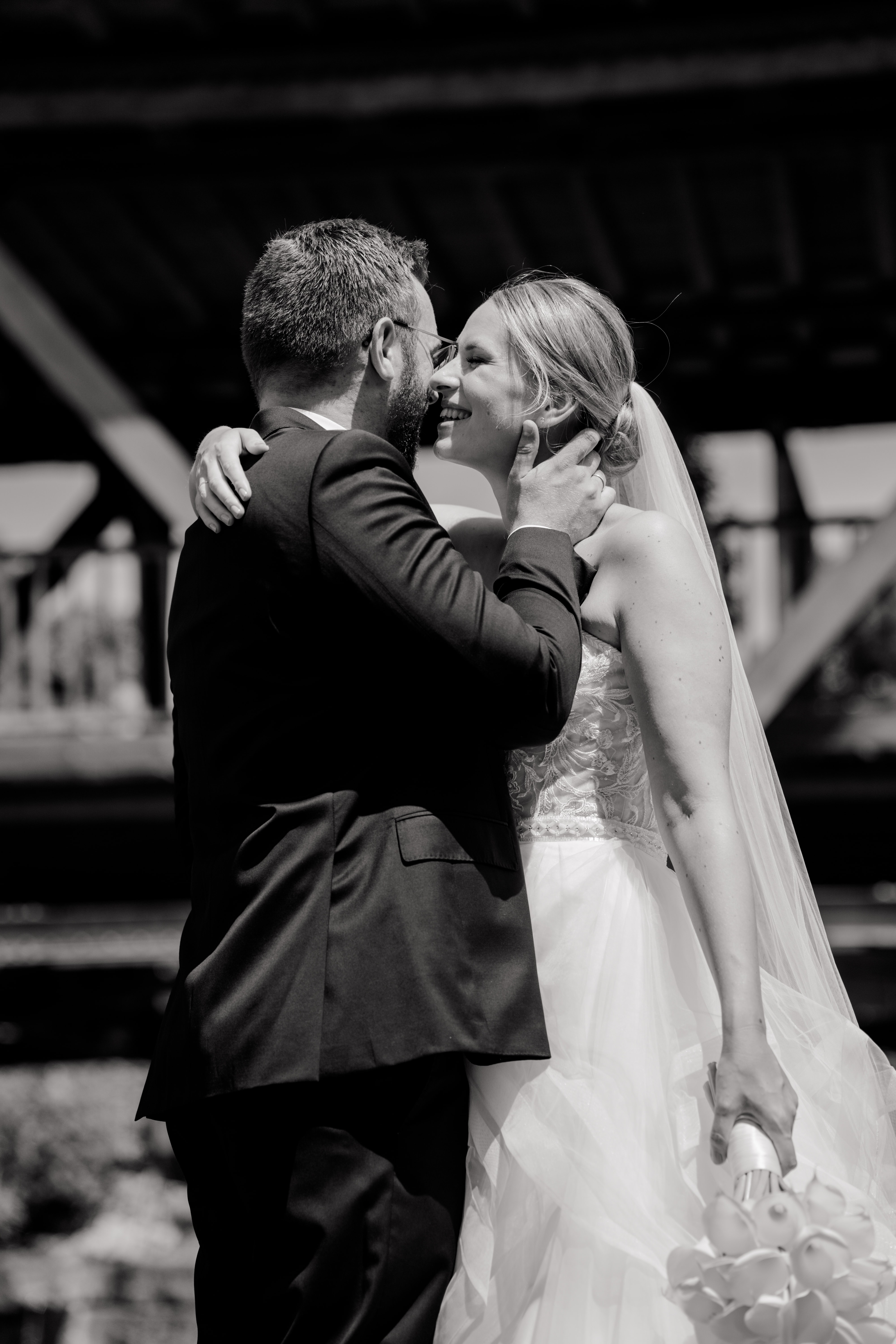 Brautpaar umarmt sich vor Holzbrücke