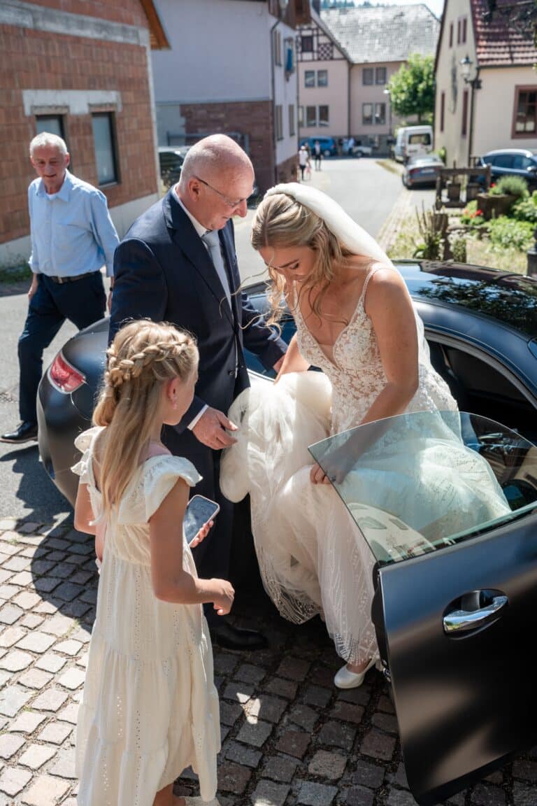 00158-florian-knusper-hochzeitsfotograf-wuerzburg-braut-steigt-aus-auto-Kloster Bronnbach