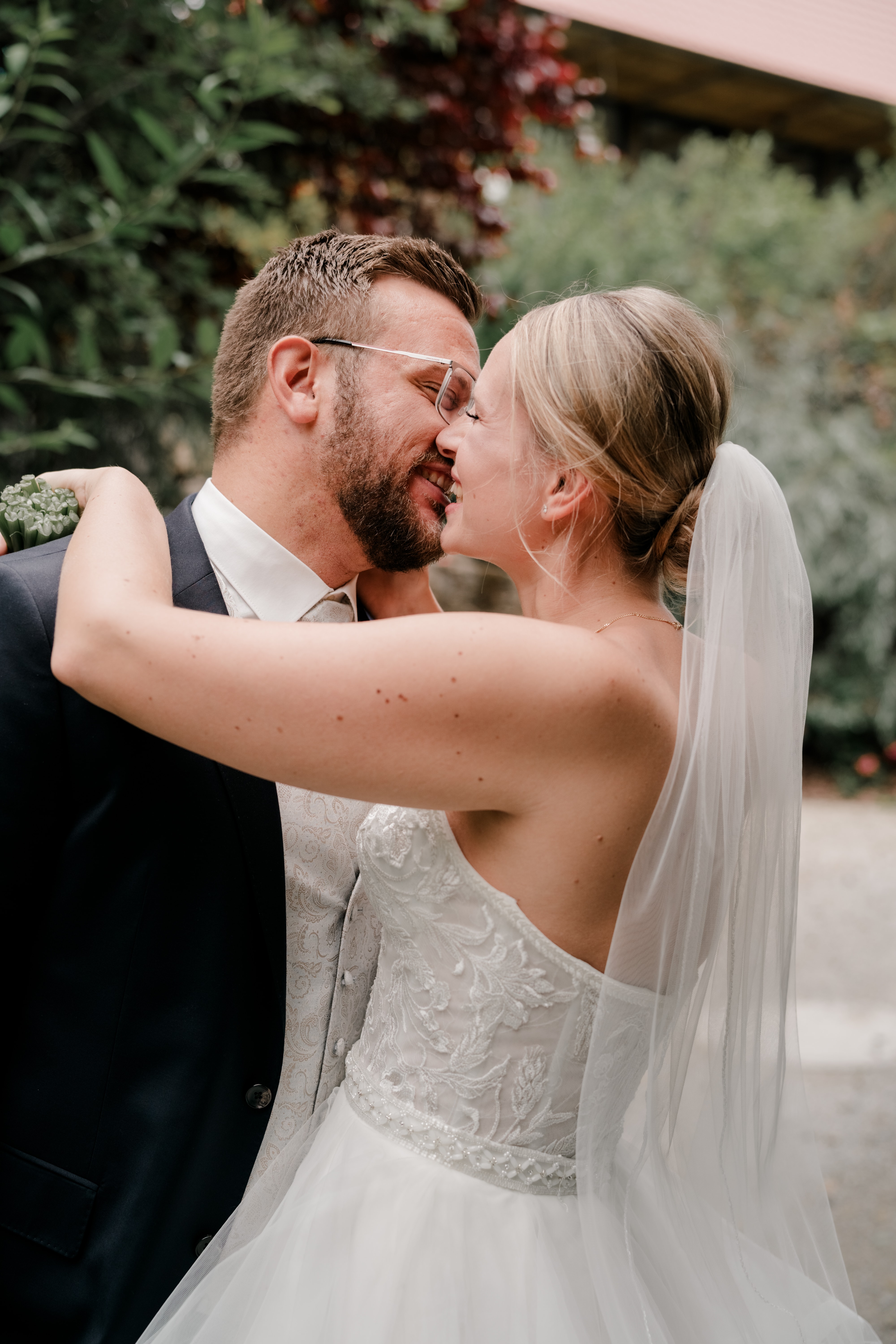 Brautpaar küsst sich im Garten.