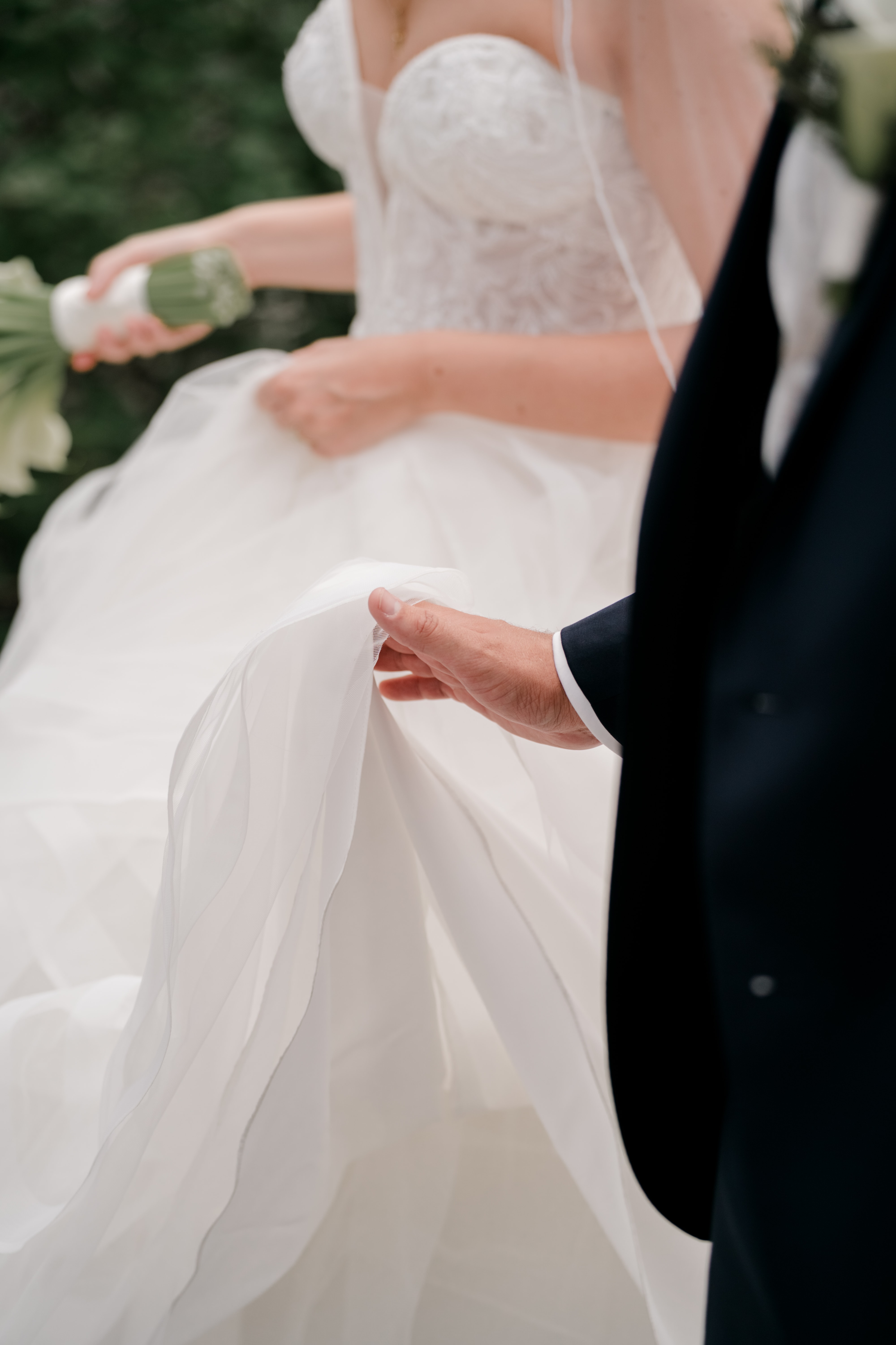 Brautpaar hält Brautkleid im Garten