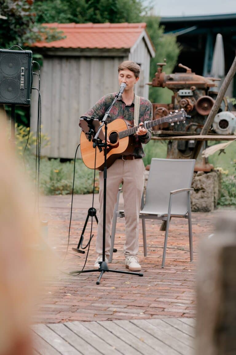 00309-florian-knusper-hochzeitsfotograf-wuerzburg-musiker-mit-gitarre-garten-Brückenbaron