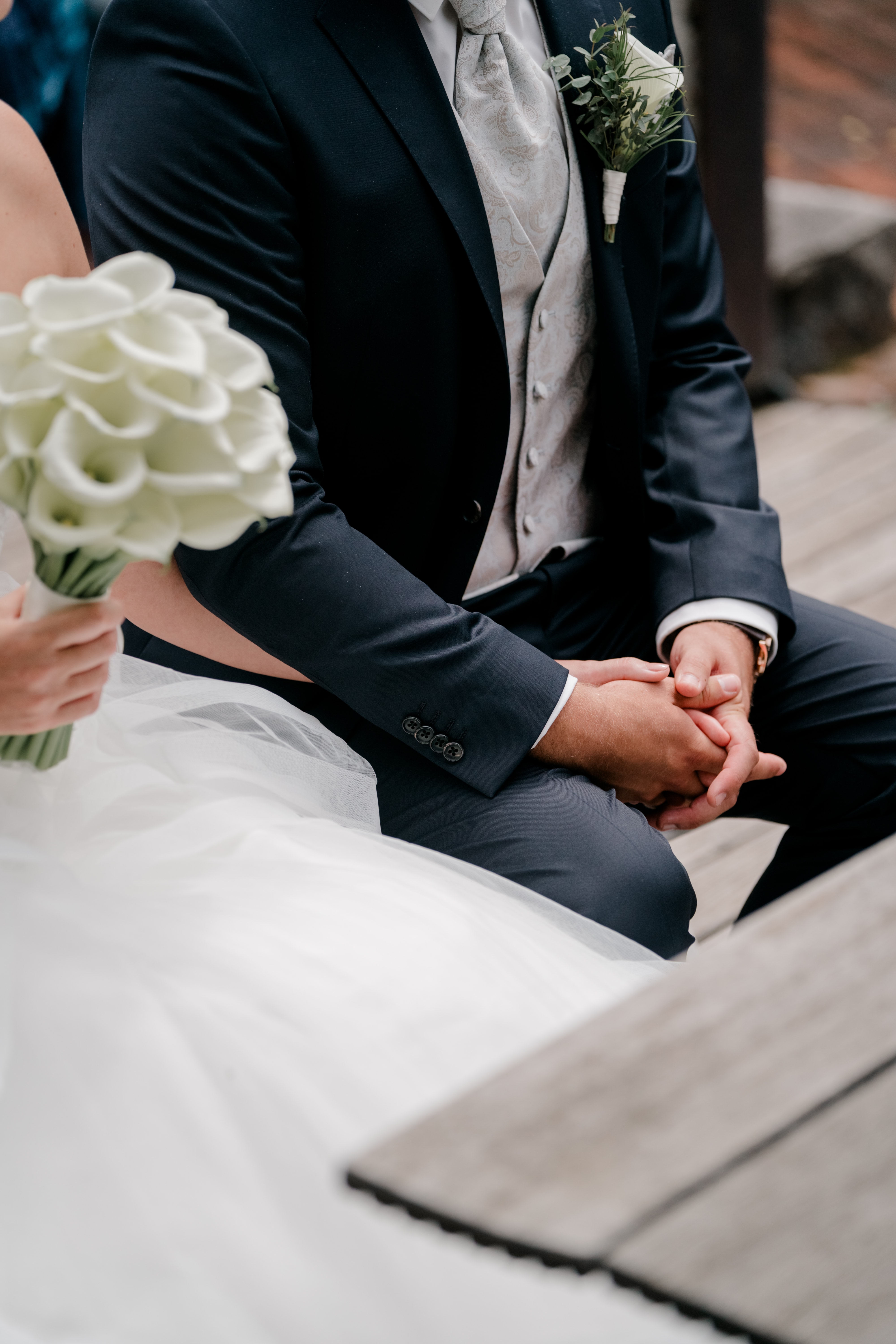 Brautpaar hält Händchen mit Blumenstrauß