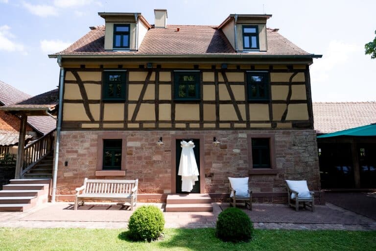 00390-florian-knusper-hochzeitsfotograf-wuerzburg-hochzeitskleid-vor-fachwerkhaus-hofgut hünnersdorf