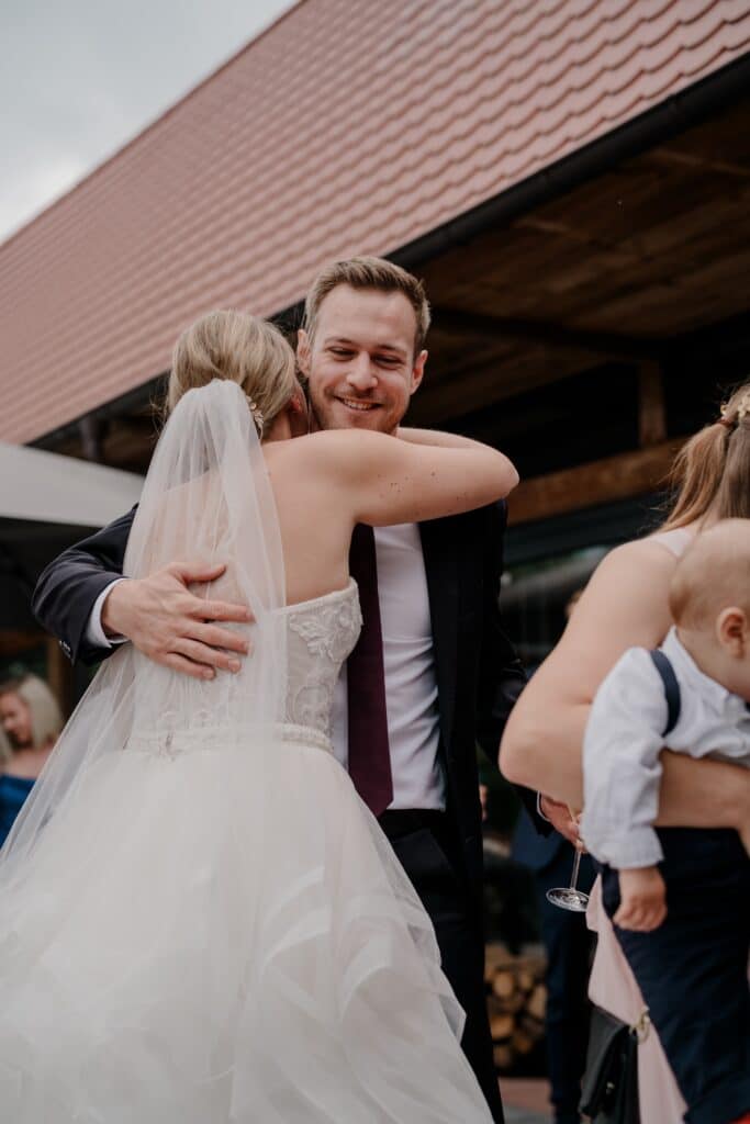 Bräutigam umarmt Braut im Freien bei Hochzeit