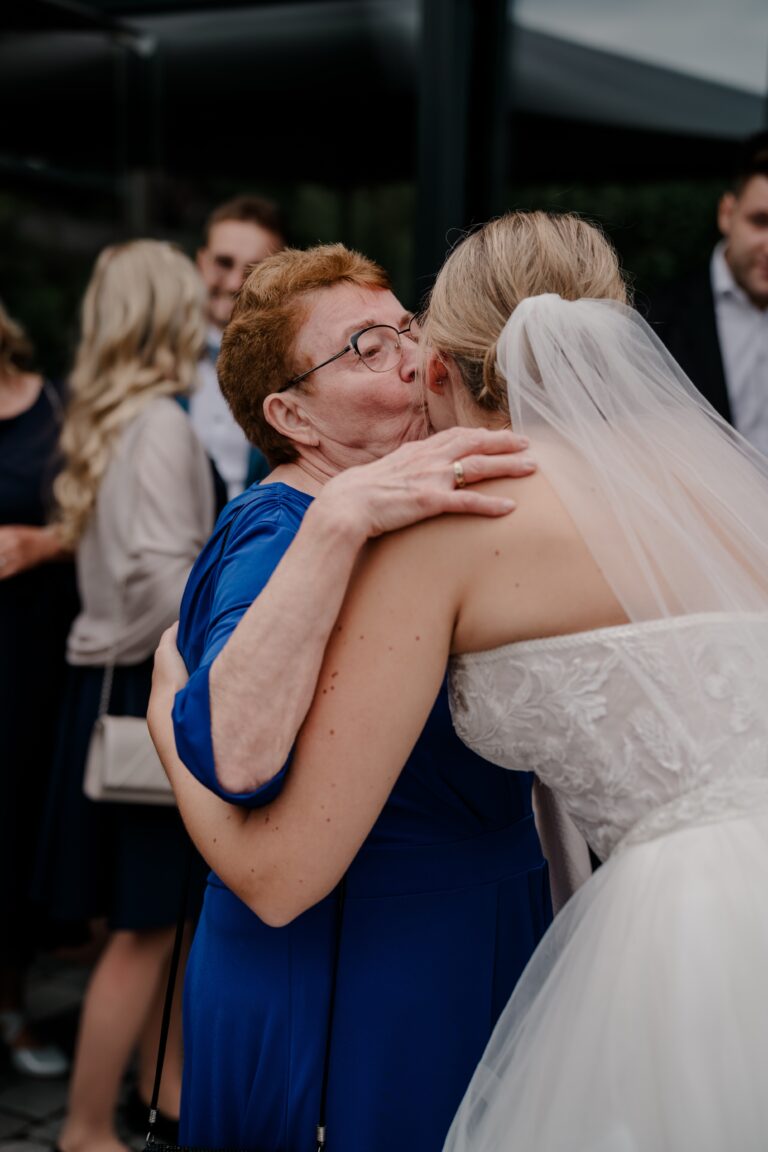 00428-florian-knusper-hochzeitsfotograf-wuerzburg-braut-umarmt-gast-Brückenbaron
