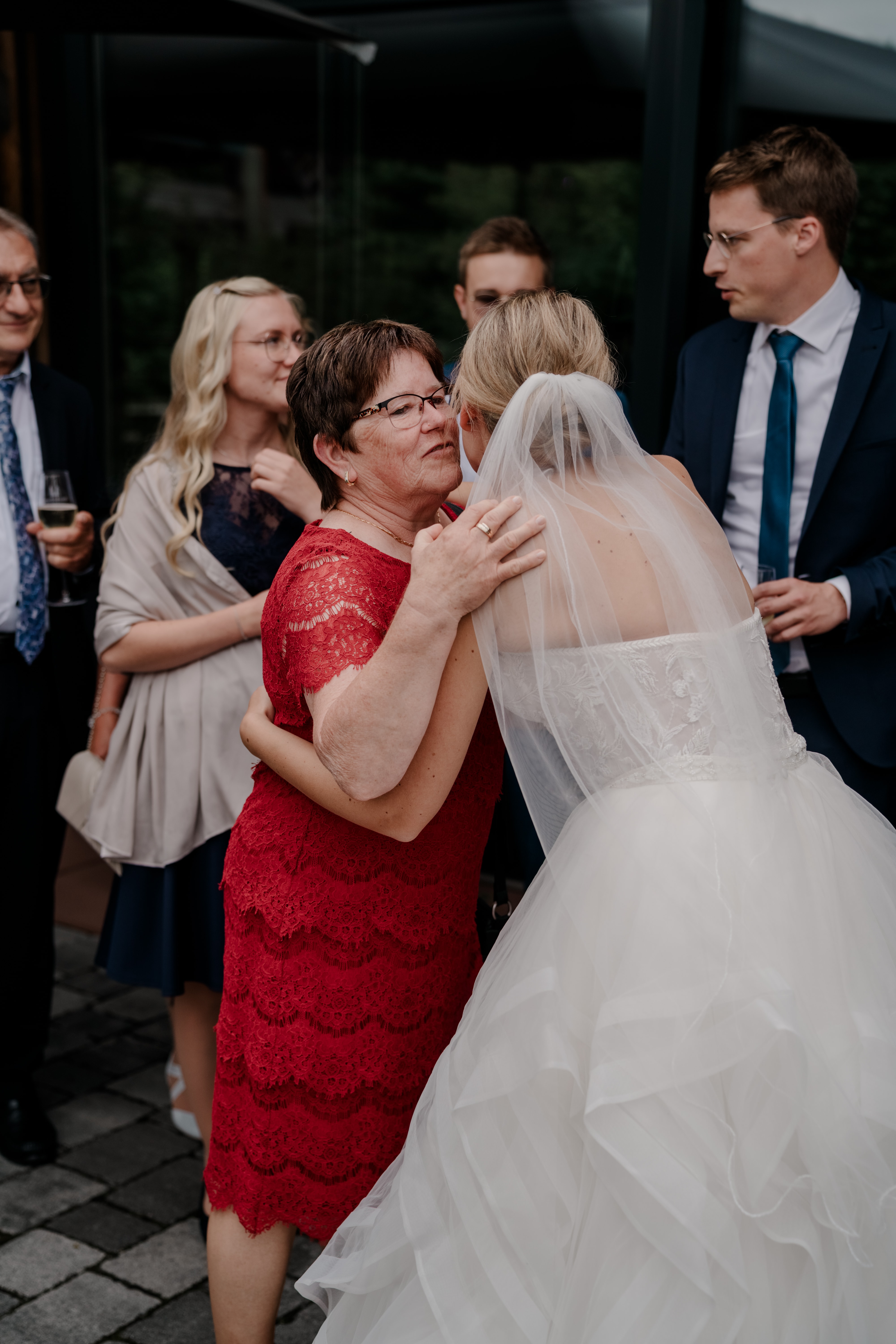 Braut umarmt Gast bei Hochzeitsfeier im Freien