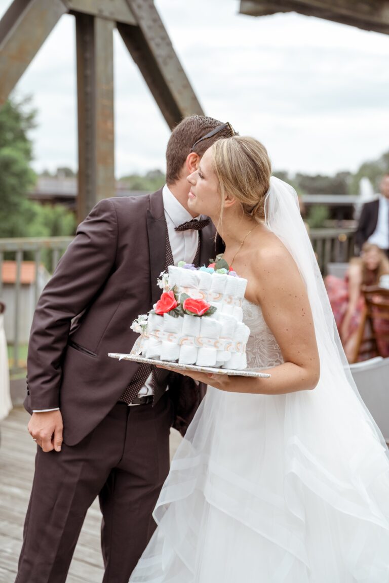 00581-florian-knusper-hochzeitsfotograf-wuerzburg-brautpaar-mit-hochzeitstorte-Brückenbaron