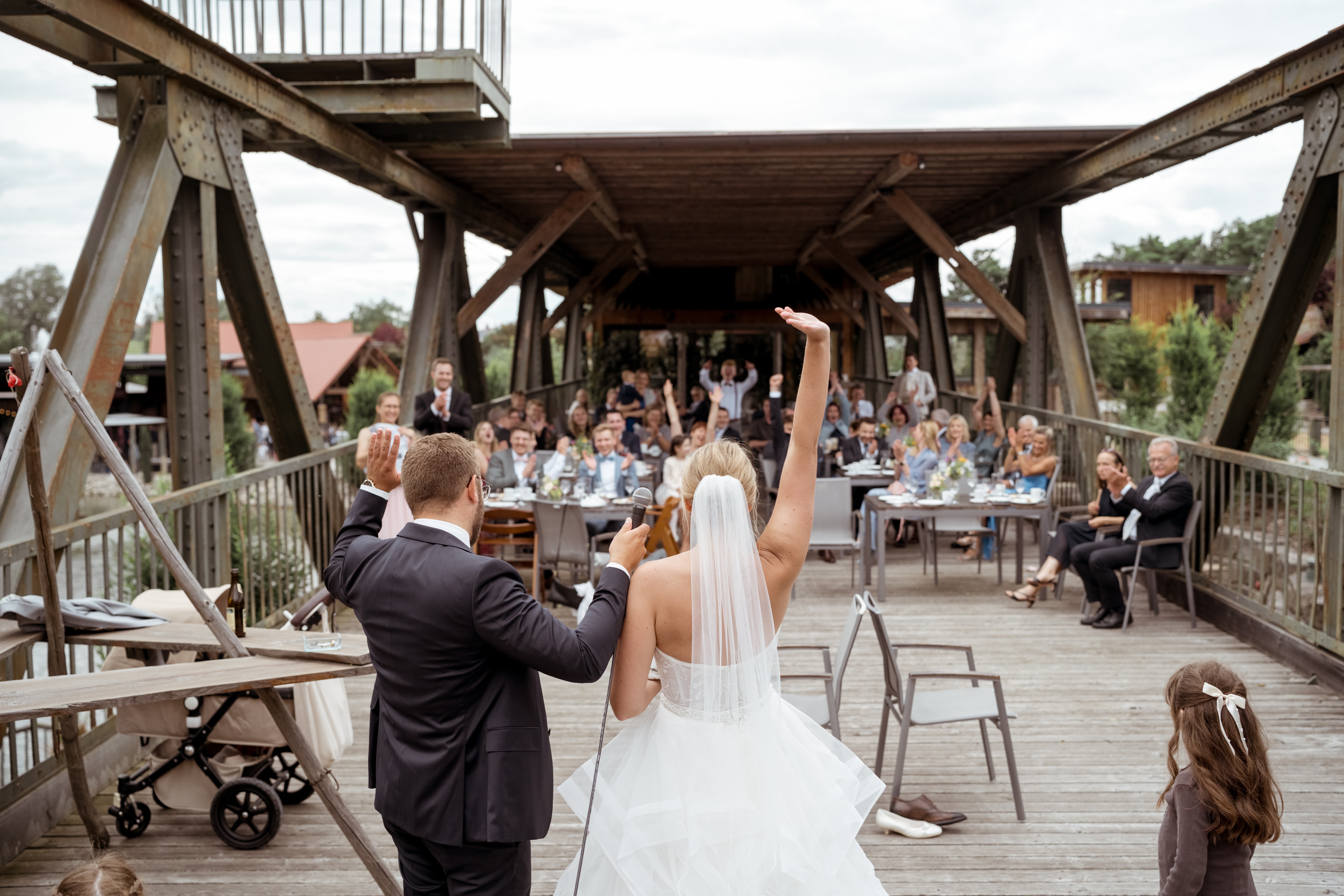 Brautpaar jubelt vor Hochzeitsgesellschaft auf Brücke