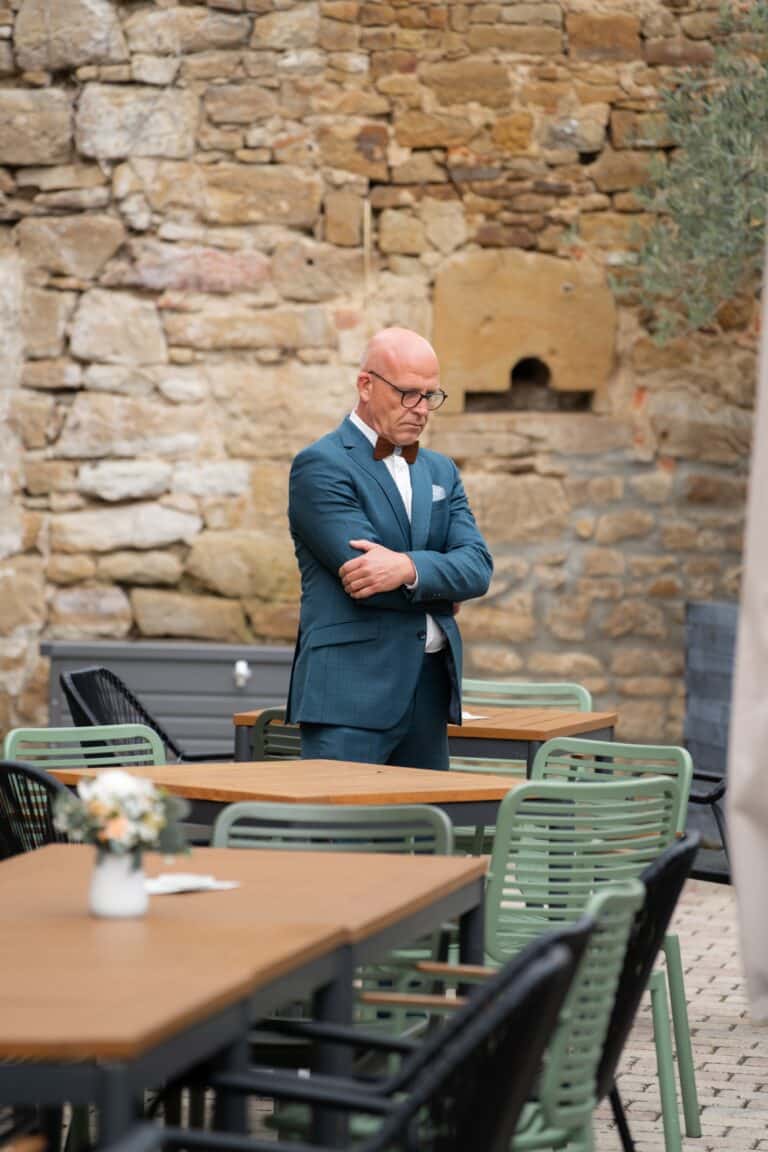 00589-2-florian-knusper-hochzeitsfotograf-wuerzburg-mann-vor-steintafel-hintergrund-Hotel Freihof Prichsenstadt