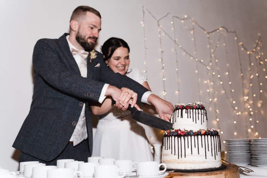 Brautpaar schneidet Hochzeitstorte an.