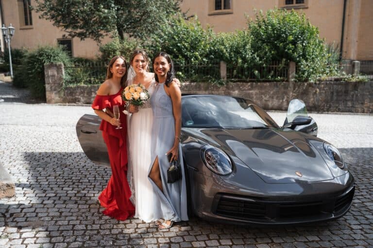 00765-florian-knusper-hochzeitsfotograf-wuerzburg-gruppe-in-abendkleidung-neben-auto
