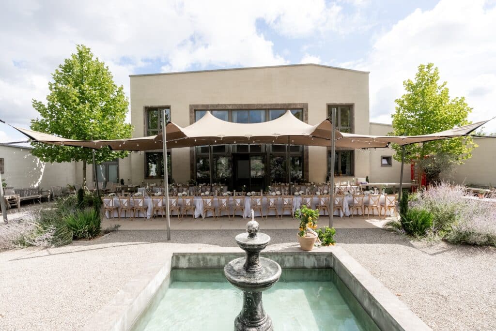 Gartenhochzeit mit festlich gedeckten Tischen und Brunnen.