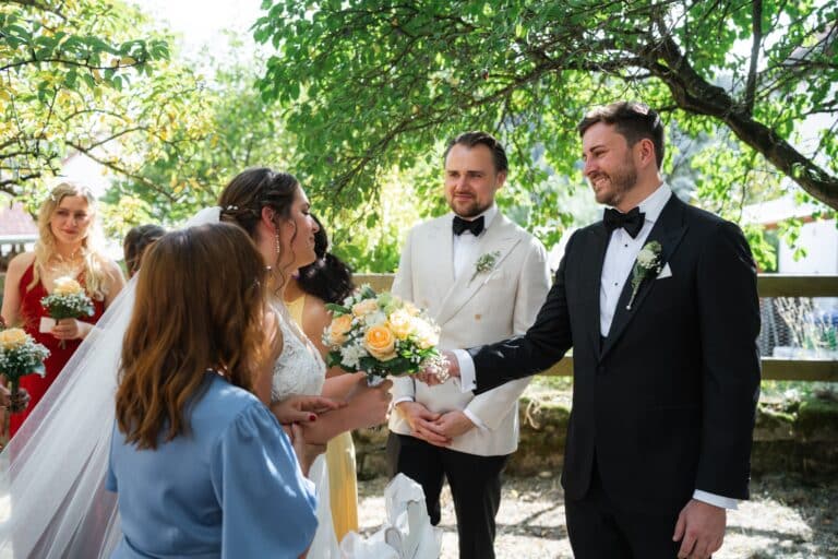 01123-florian-knusper-hochzeitsfotograf-wuerzburg-brautpaar-mit-gaesten-im-garten