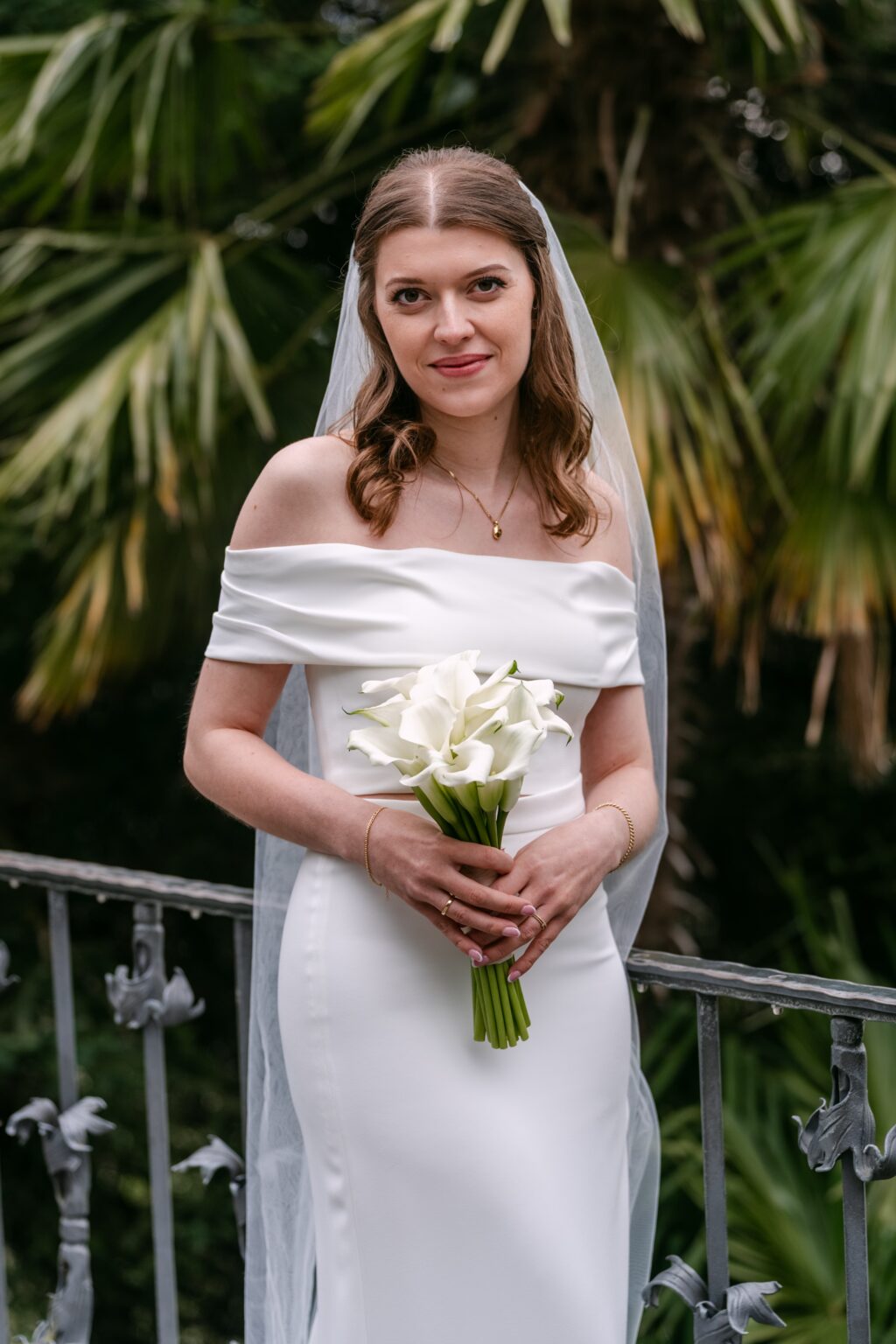 Braut mit Calla-Strauß auf Terrasse im Garten