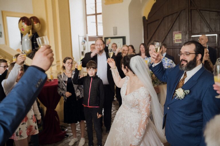 01281-florian-knusper-hochzeitsfotograf-wuerzburg-brautpaar-mit-gaesten-toast-Schloss Oberschwarzach