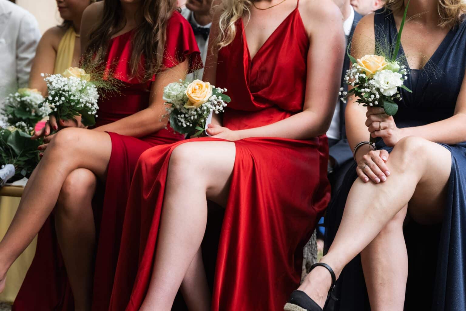 Gäste in eleganten Kleidern mit Blumensträußen.