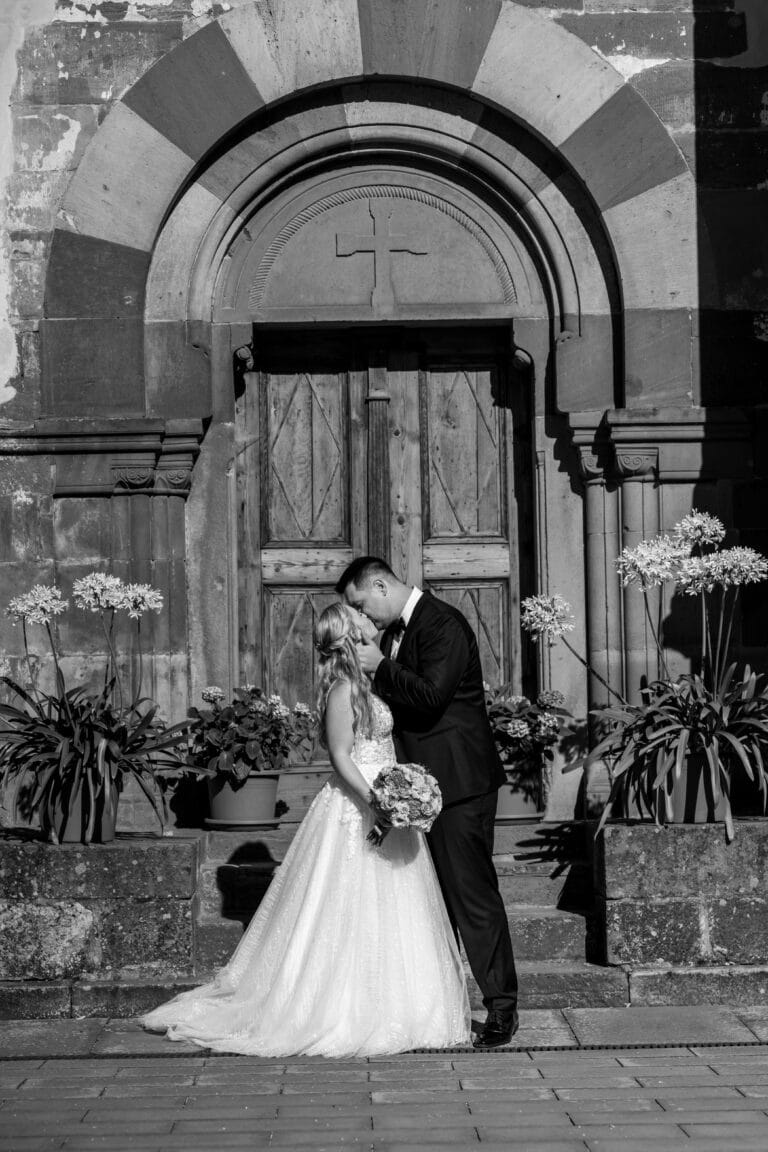 01453-2-florian-knusper-hochzeitsfotograf-wuerzburg-brautpaar-vor-kirchentuer-Kloster Bronnbach