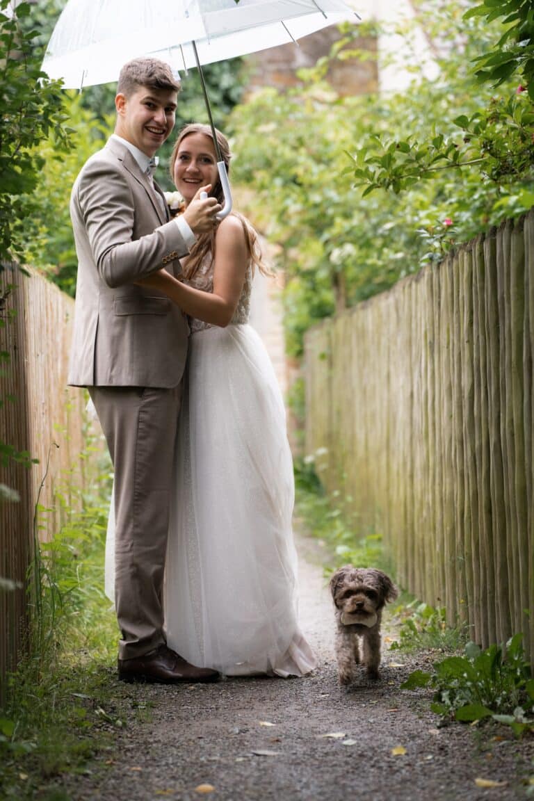 01935-florian-knusper-hochzeitsfotograf-wuerzburg-brautpaar-im-garten-mit-hund-Hotel Freihof Prichsenstadt