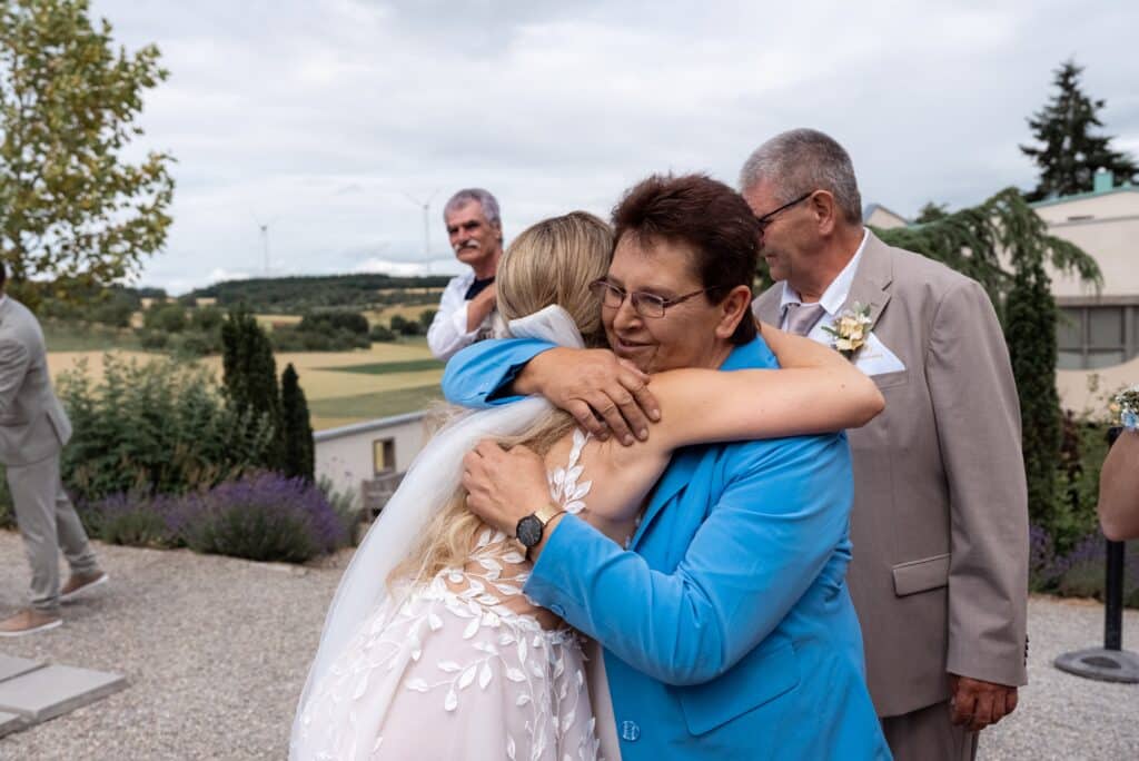 Brautpaar umarmt Gäste im Freien bei Hochzeit