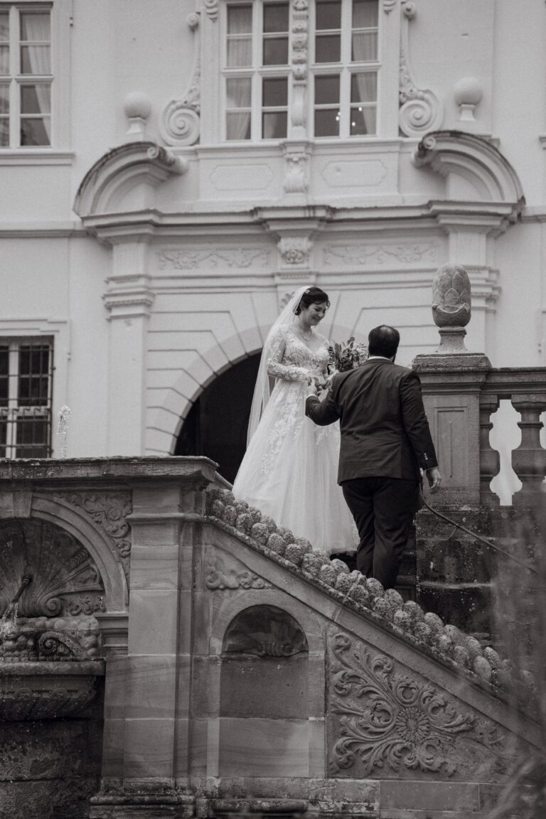 02256-2-florian-knusper-hochzeitsfotograf-wuerzburg-brautpaar-auf-treppe-Schloss Oberschwarzach