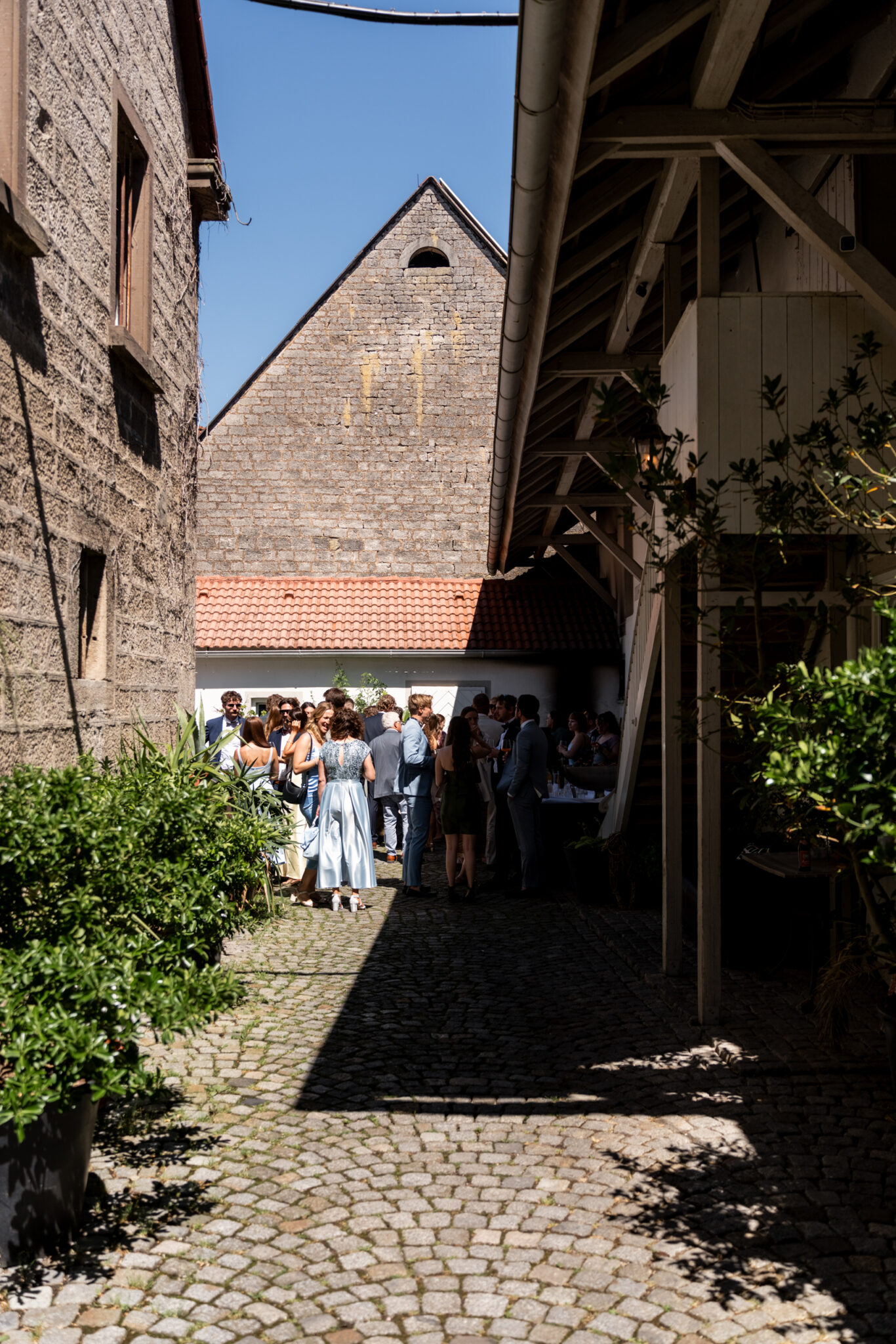 Hochzeitsgäste beim Sektempfang im Hof