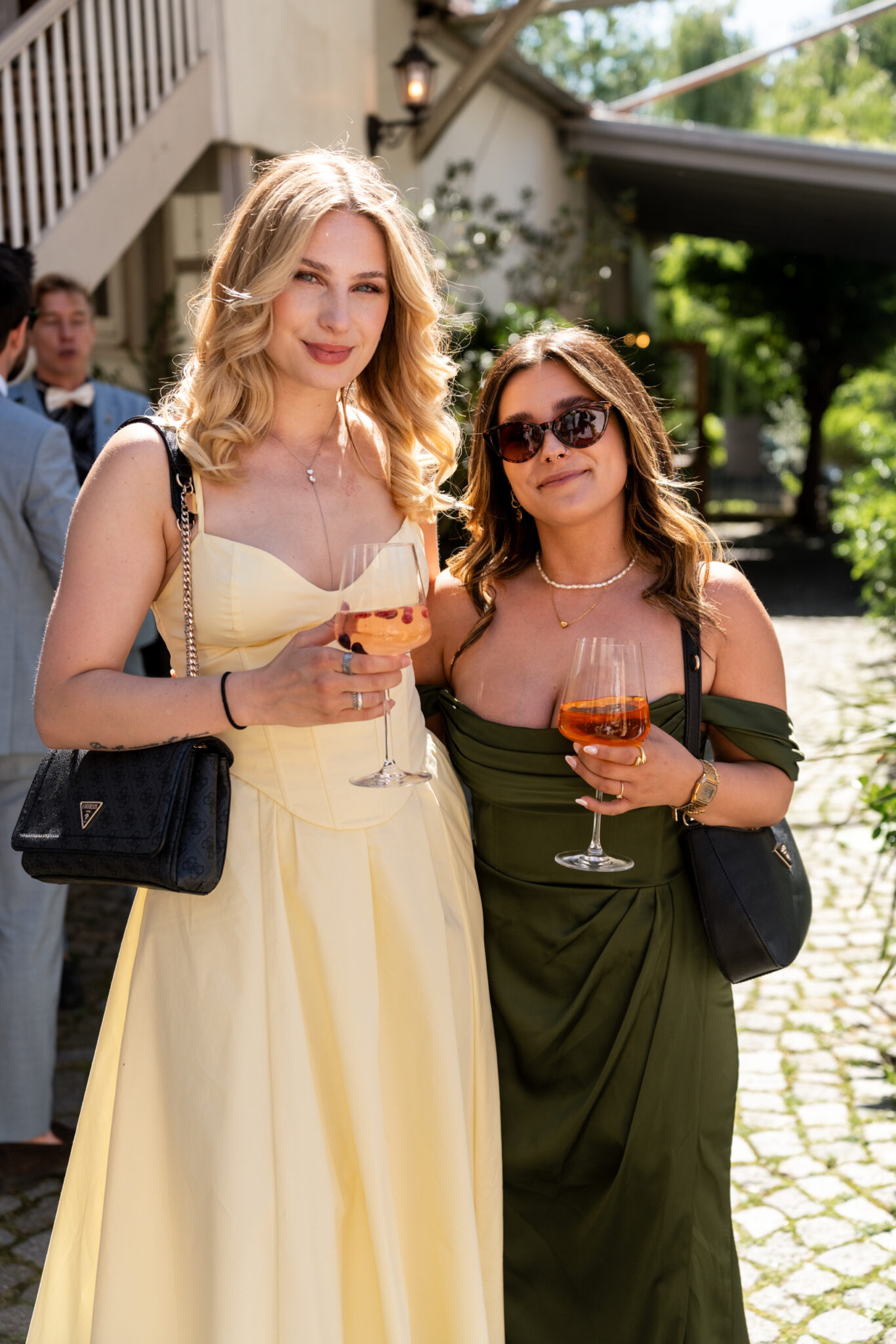 Hochzeitsgäste mit Aperitif im sonnigen Gartenhof