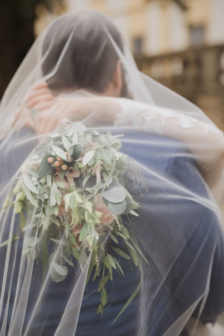 02488-florian-knusper-hochzeitsfotograf-wuerzburg-brautpaar-umarmung-mit-schleier-Schloss Oberschwarzach