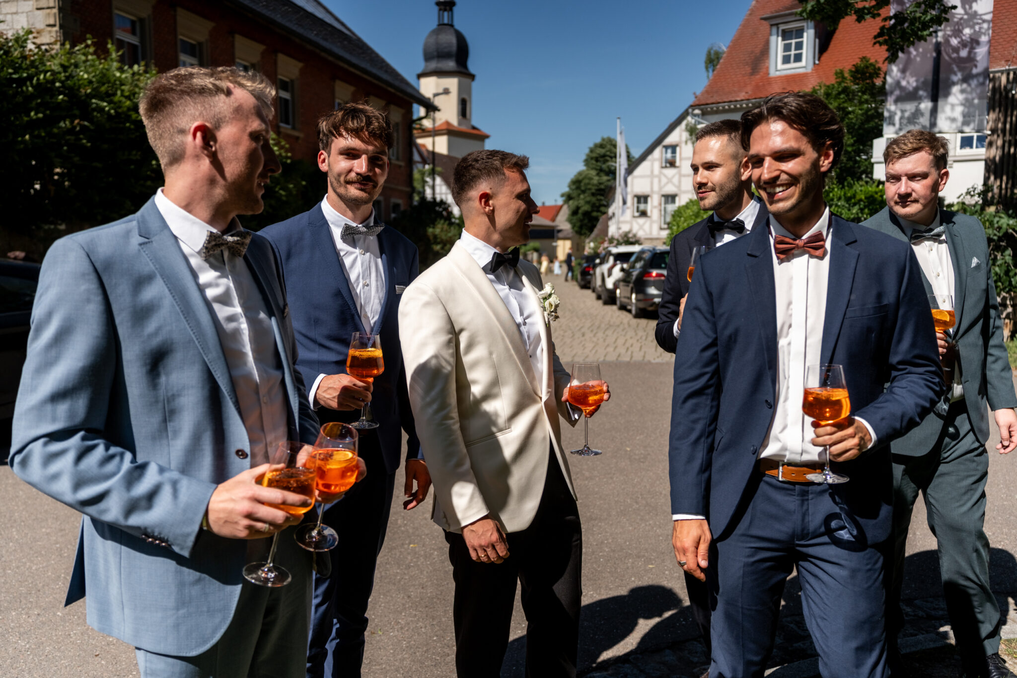 Hochzeitsgäste im Anzug mit Aperitif vor Kirche