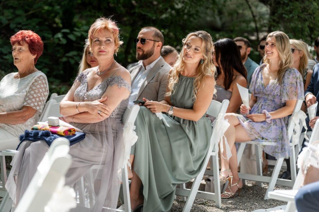 Gäste sitzen bei sonniger Hochzeit im Freien.