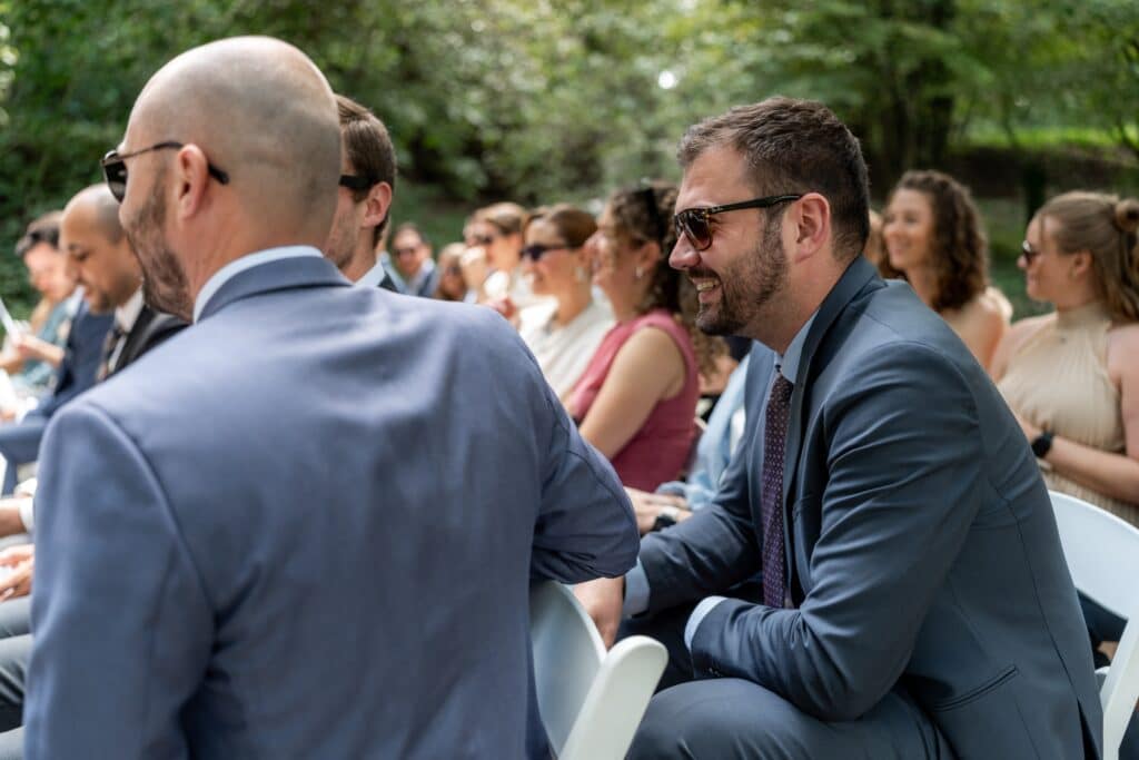 Hochzeitsgäste sitzen im Freien und lachen.