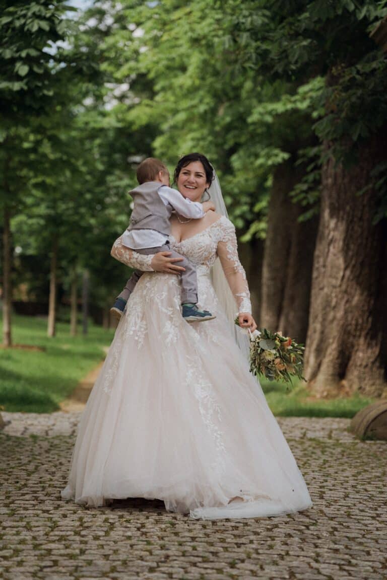 03306-florian-knusper-hochzeitsfotograf-wuerzburg-braut-mit-kind-im-garten-Schloss Oberschwarzach