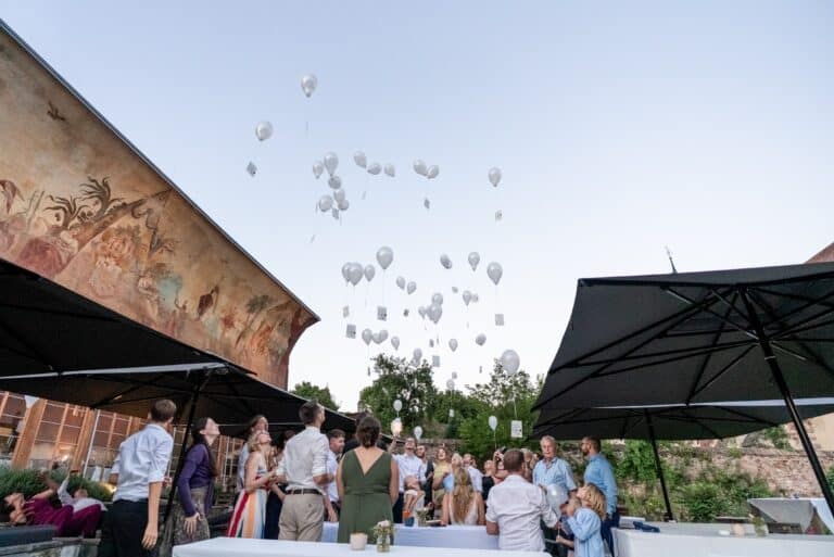 03405-florian-knusper-hochzeitsfotograf-wuerzburg-gaeste-mit-luftballons-Kloster Bronnbach