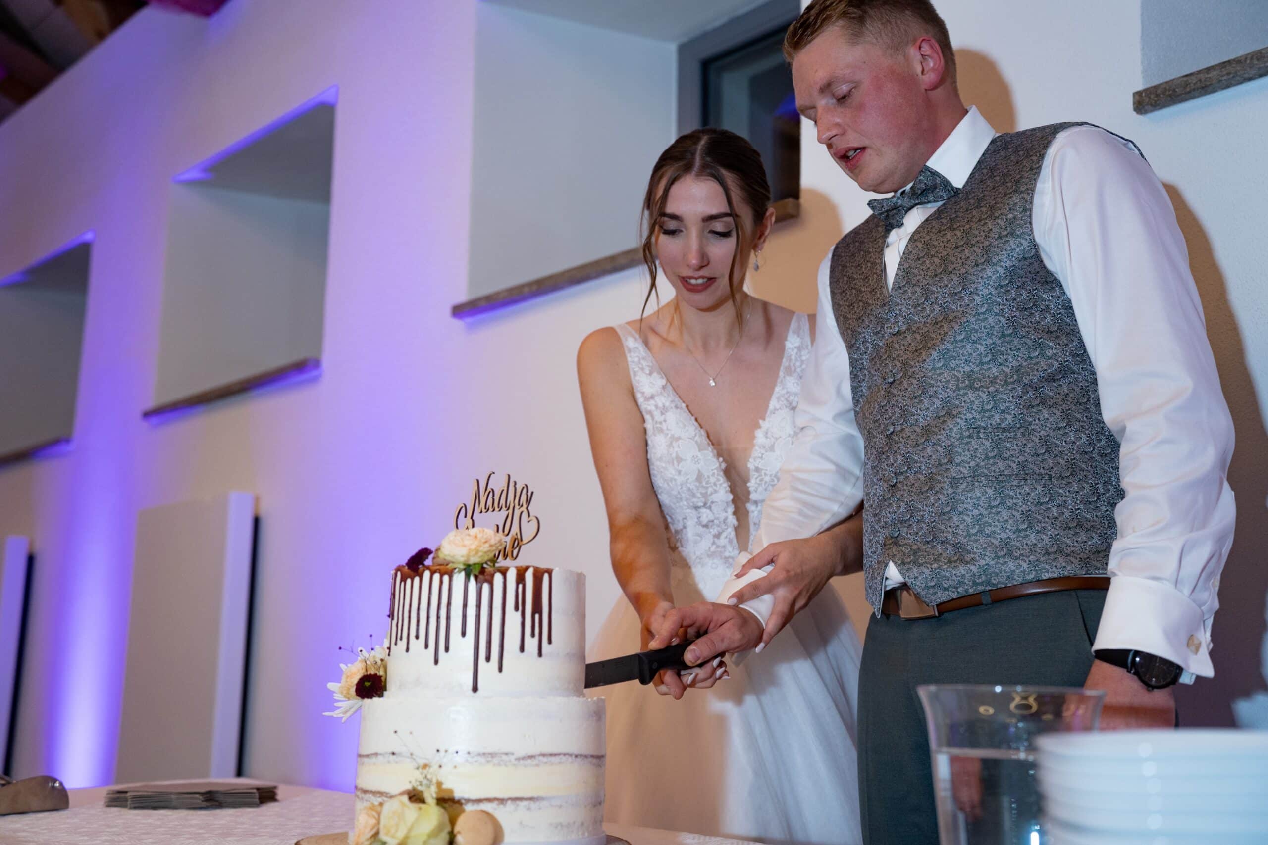 Brautpaar schneidet Hochzeitstorte an.