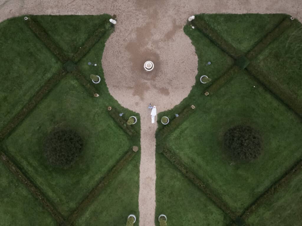Brautpaar auf Gartenweg in symmetrischem Park.
