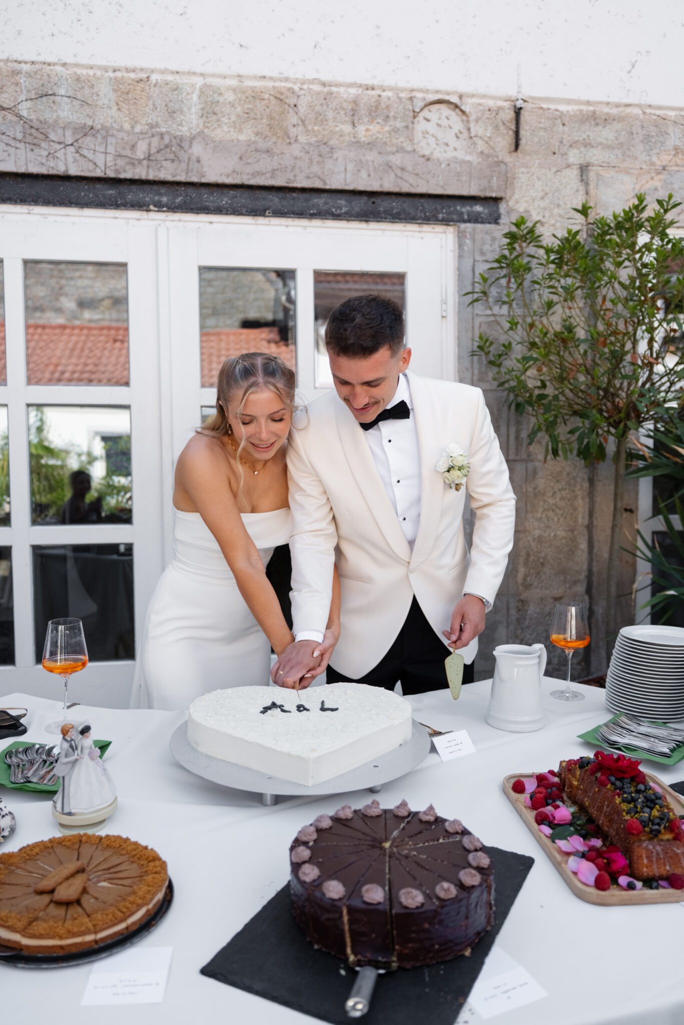 Brautpaar schneidet herzförmige Hochzeitstorte am Buffet