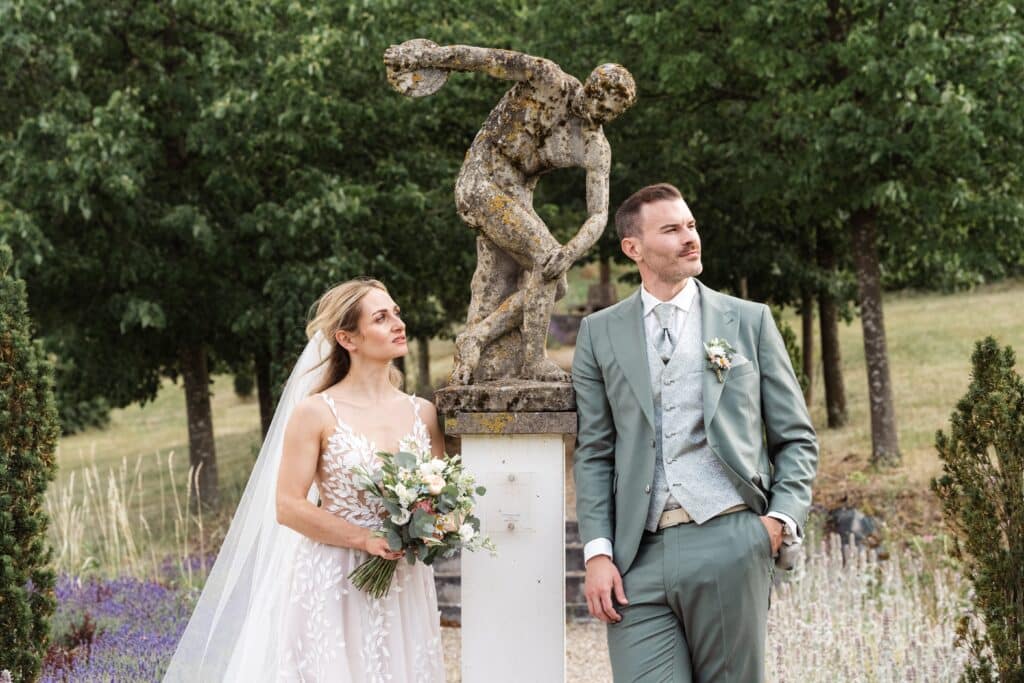 natürliche hochzeitsposen brautpaar brust an brust elegante und echte hochzeitsfotos Brautpaar posiert neben antiker Skulptur im Garten